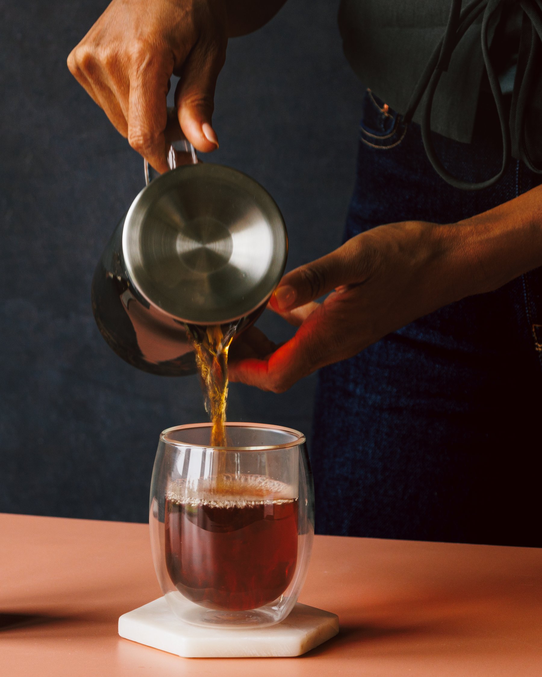 Pouring hot water from a kettle into a glass of Majestic Earl Grey